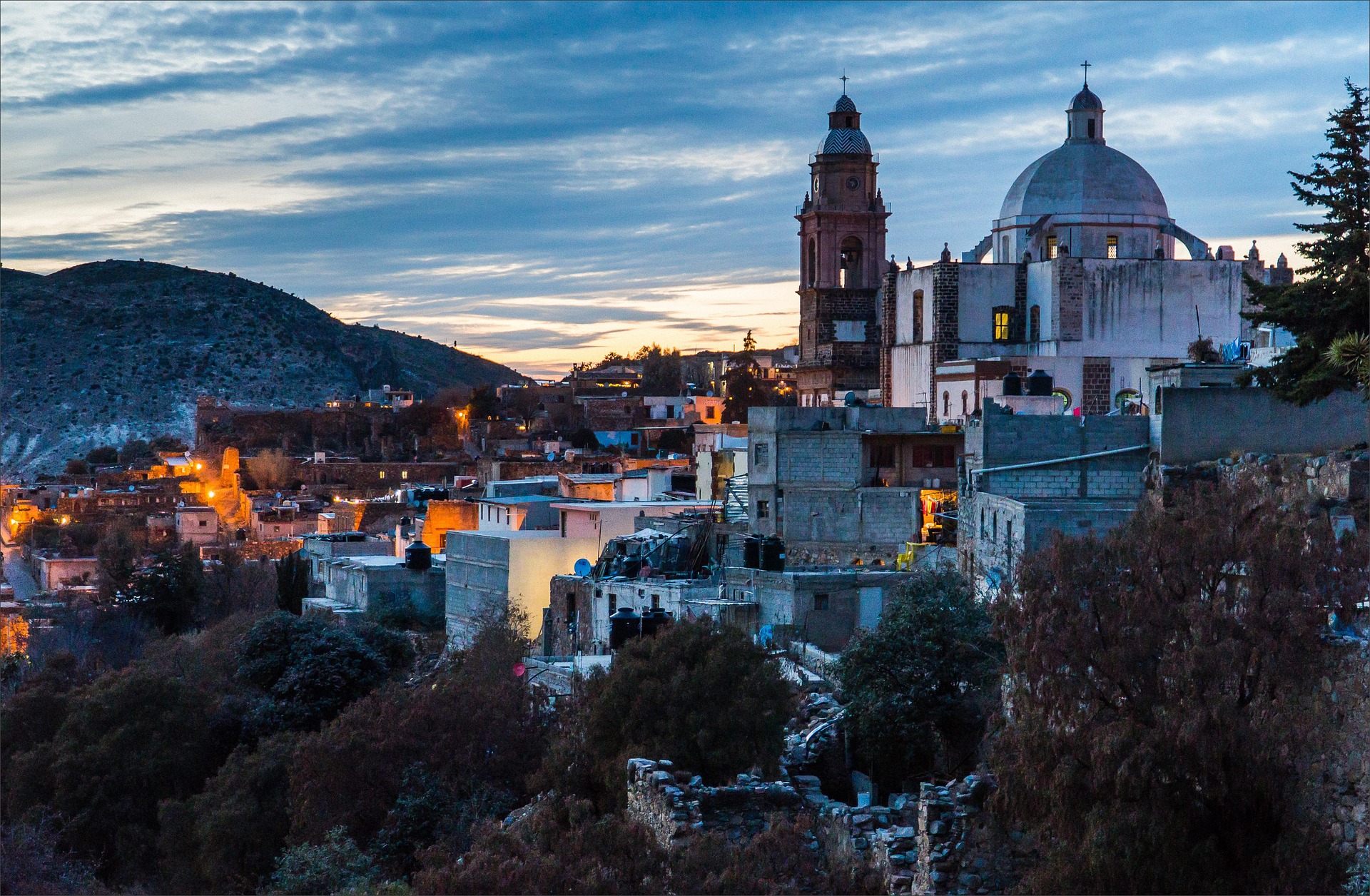 Hillside town at dusk with a domed church and bell tower